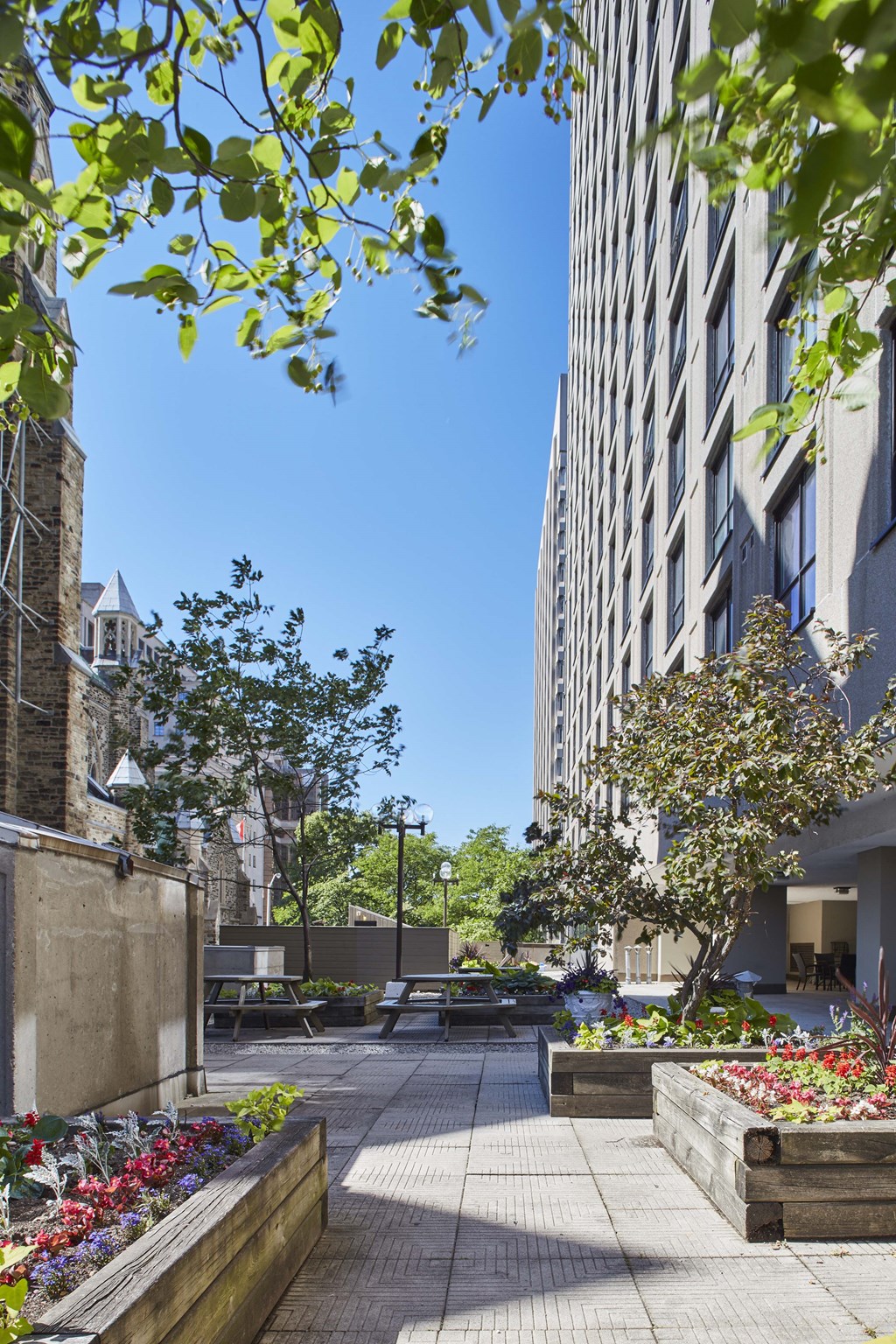 a courtyard with benches and trees next to a tall building