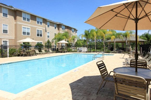 a swimming pool with a table and chairs next to a building