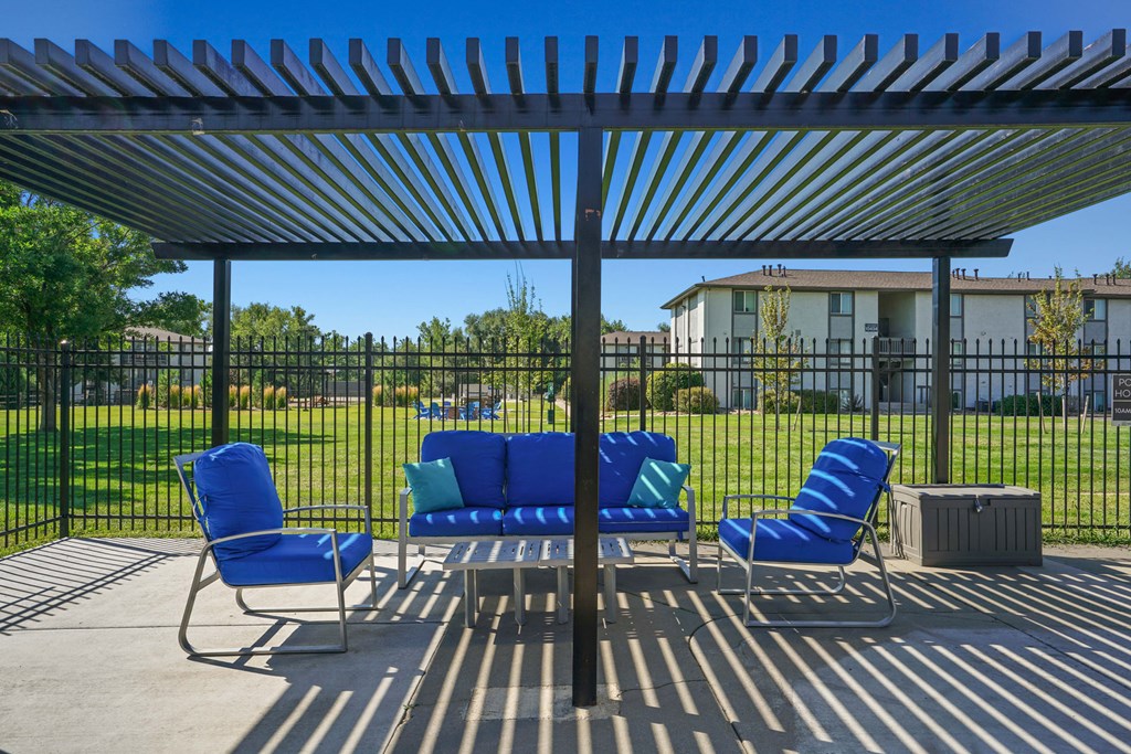 a covered patio with blue chairs and a black metal fence