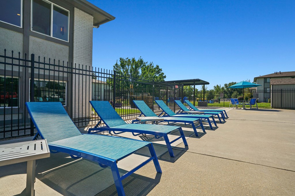 a row of blue picnic tables and chairs in front of a building