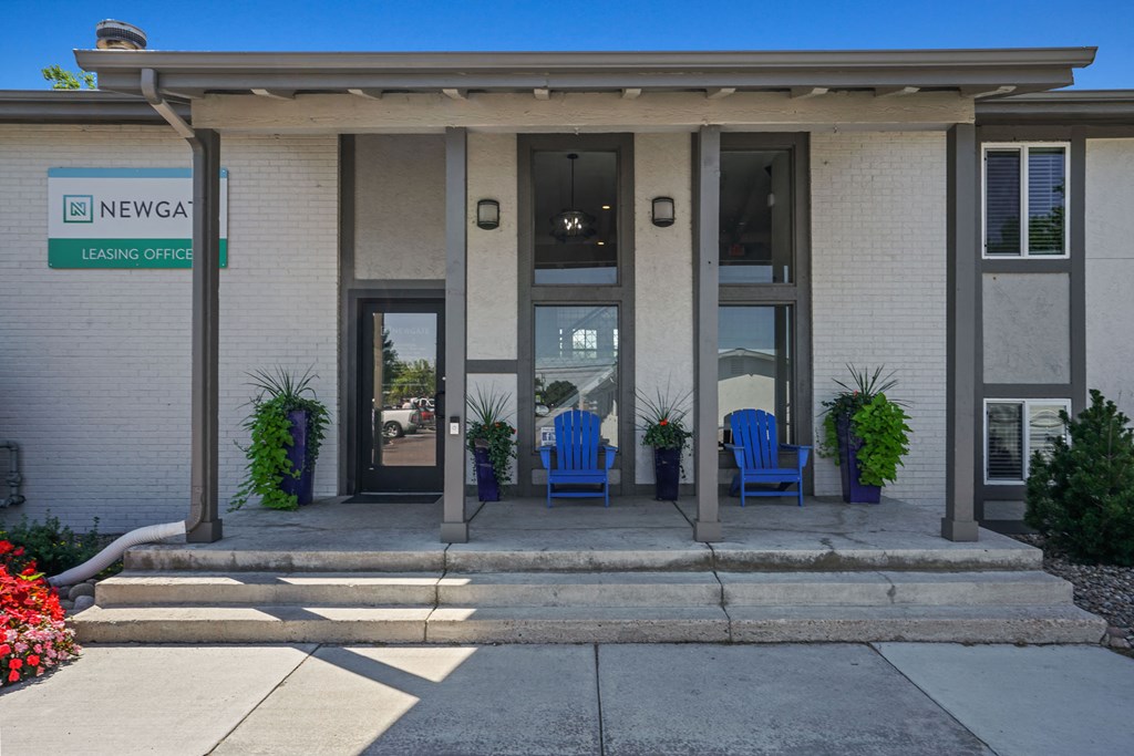 a white building with two blue chairs in front of it