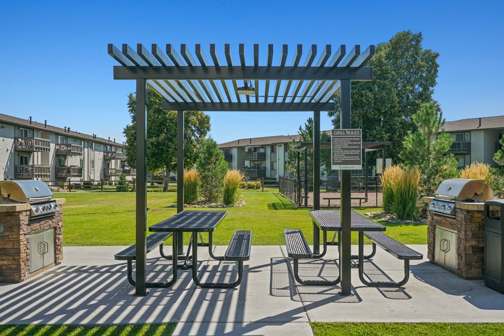 a picnic area with benches and tables in front of an apartment building