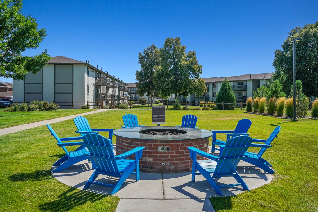 our fire pit is surrounded chairs and lawn chairs