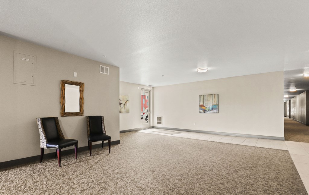 an empty living room with two chairs and a carpeted floor