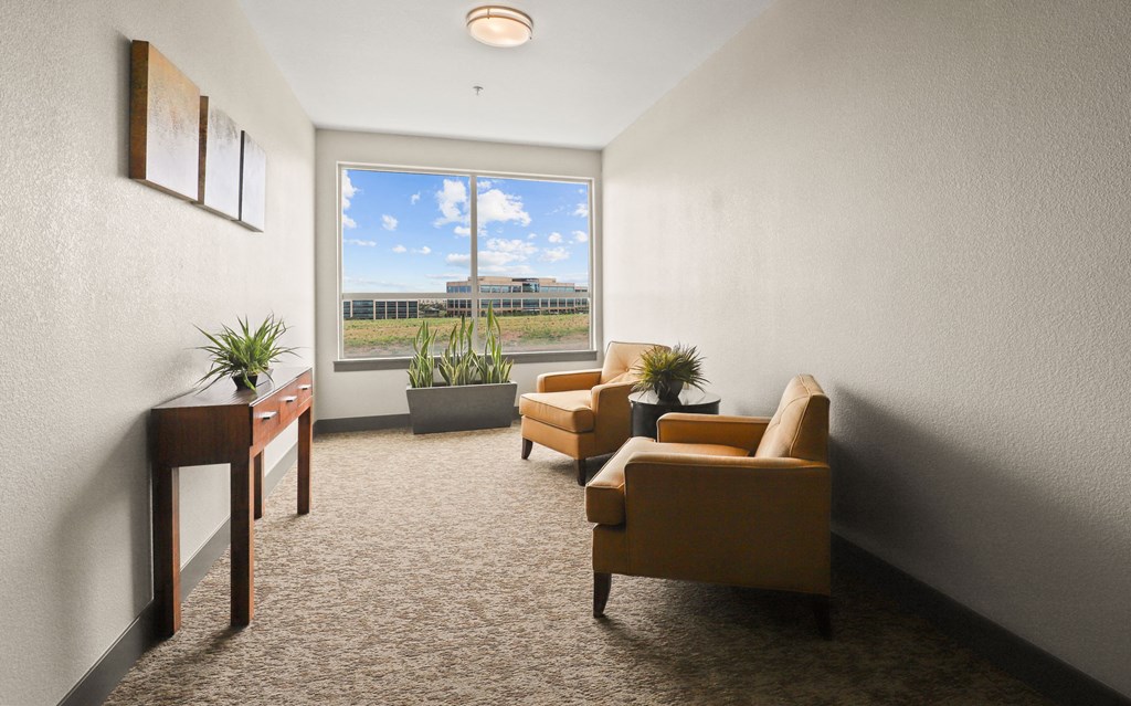 a living room with chairs and a desk and a window