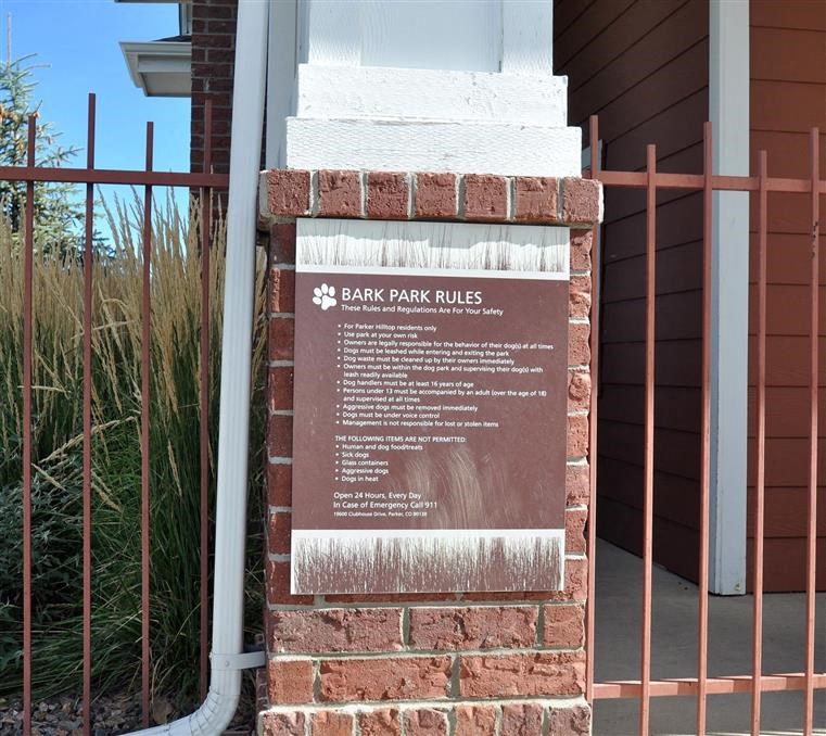 a brick sign for the bank park rules in front of a fence
