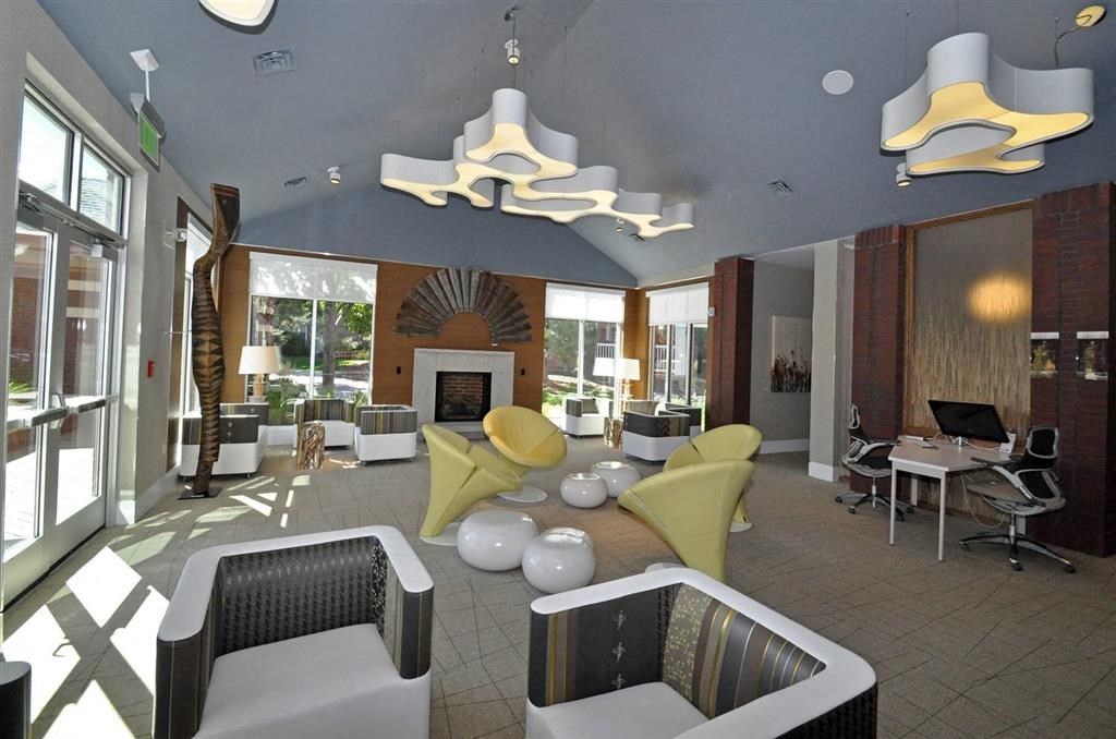 the lobby of a hotel with chairs and a fireplace