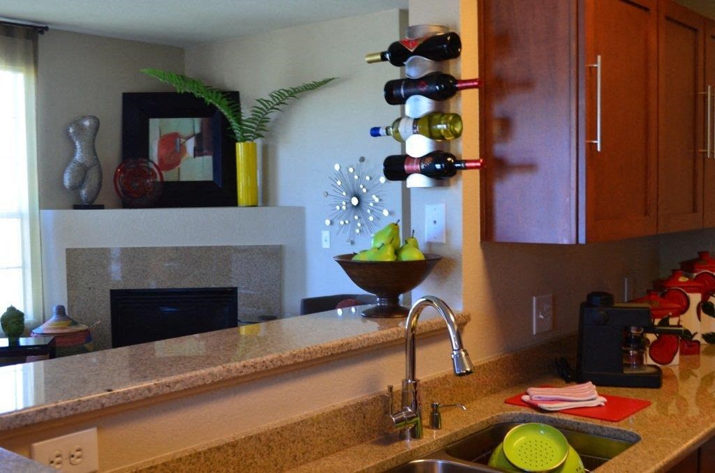 a kitchen with a sink and some wine bottles on the wall