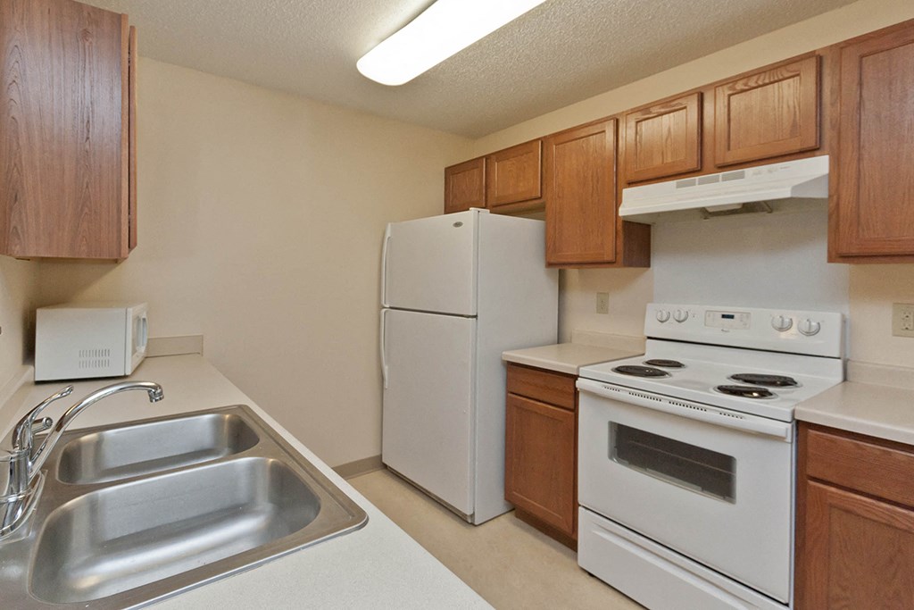 a kitchen with white appliances and wooden cabinets and a sink