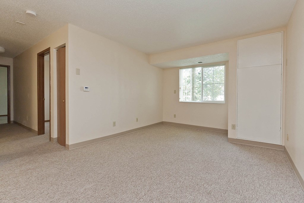 an empty living room with white walls and a window
