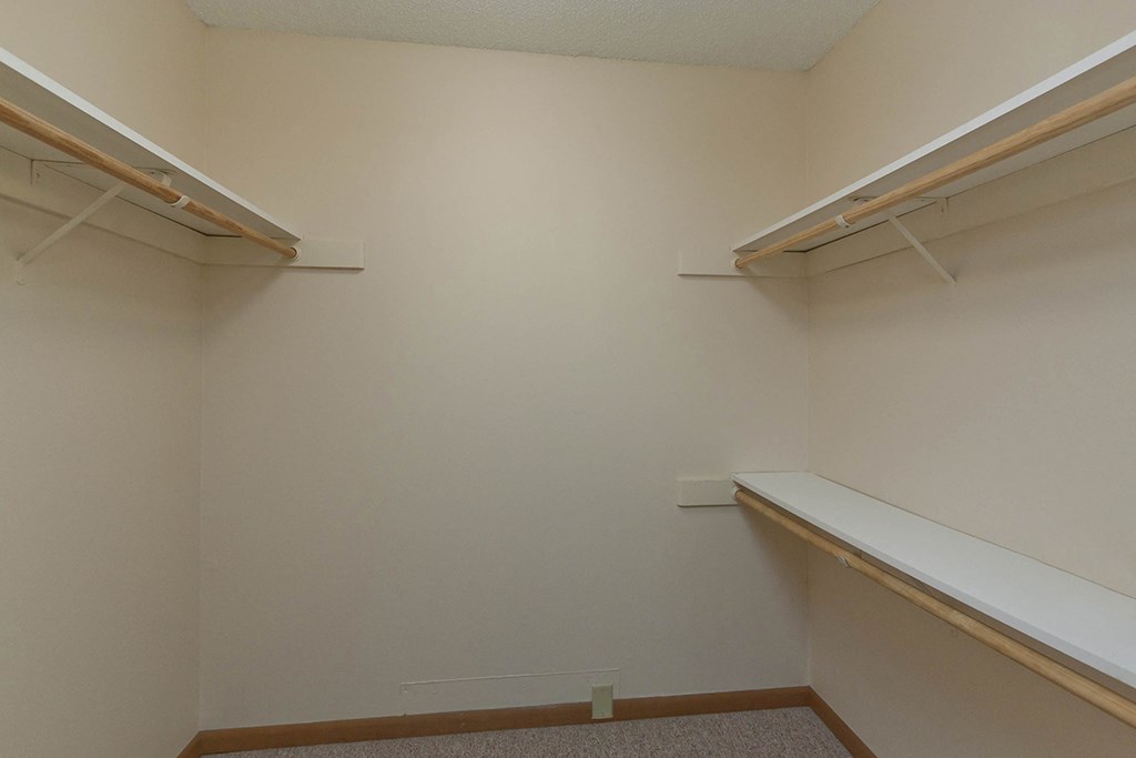 a walk in closet with two shelves and a bench