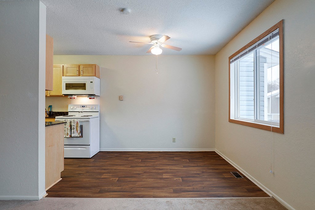 an empty kitchen with a ceiling fan and a window