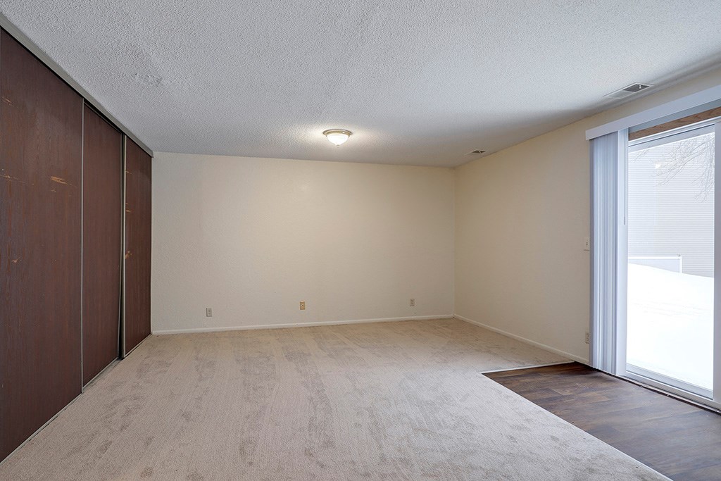 an empty living room with a closet and a window