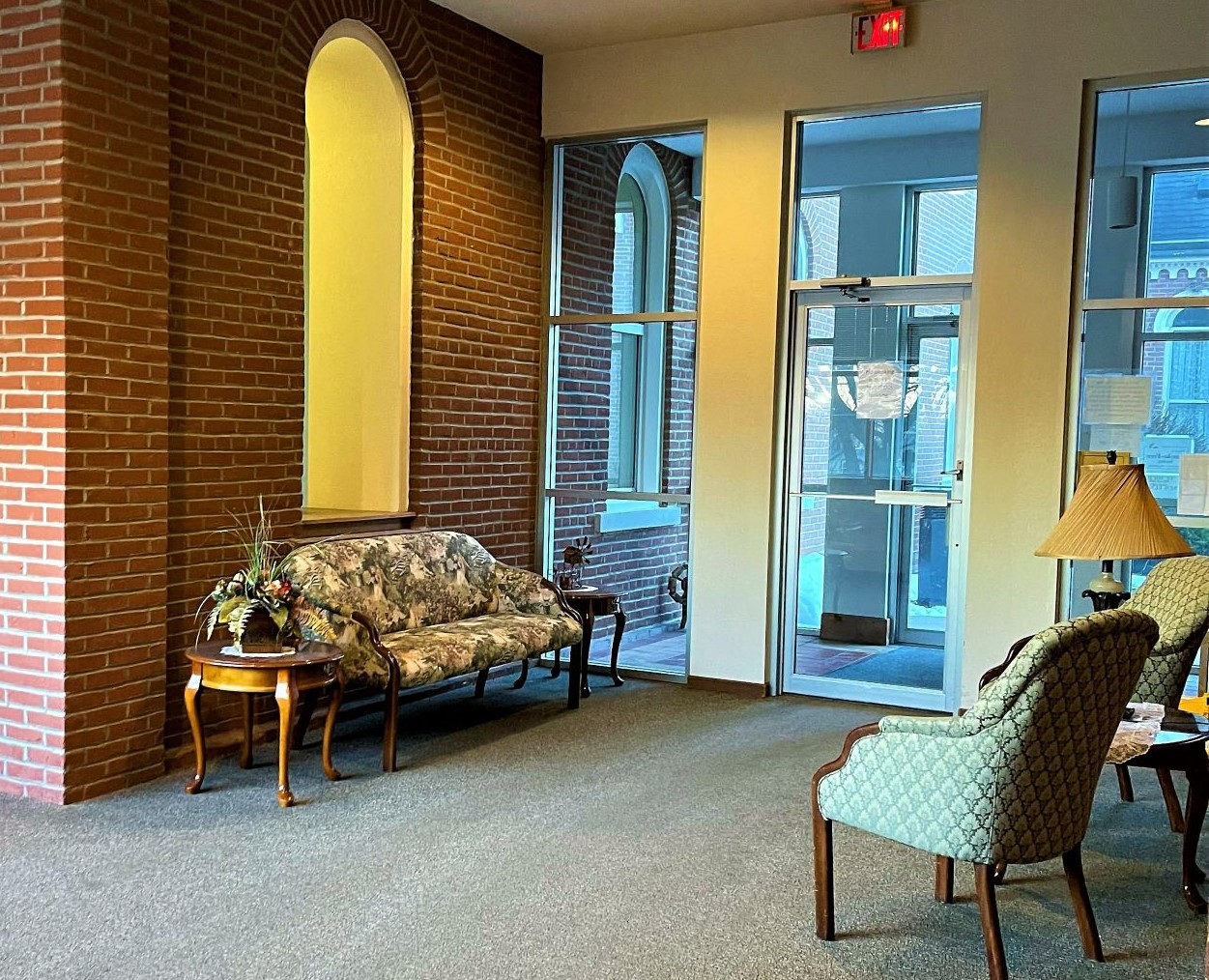 a living room with a couch and chairs and a brick wall
