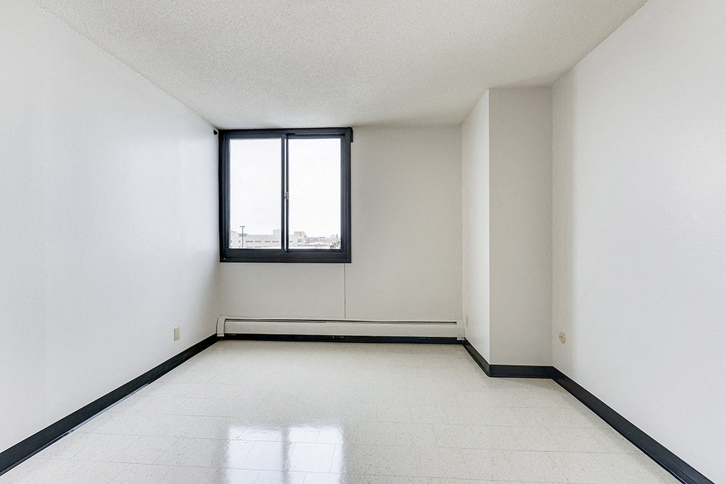 an empty room with a window and white walls