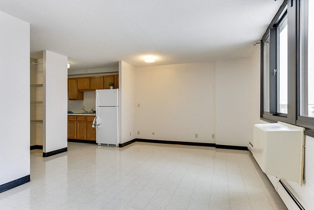 an empty living room and kitchen with a refrigerator