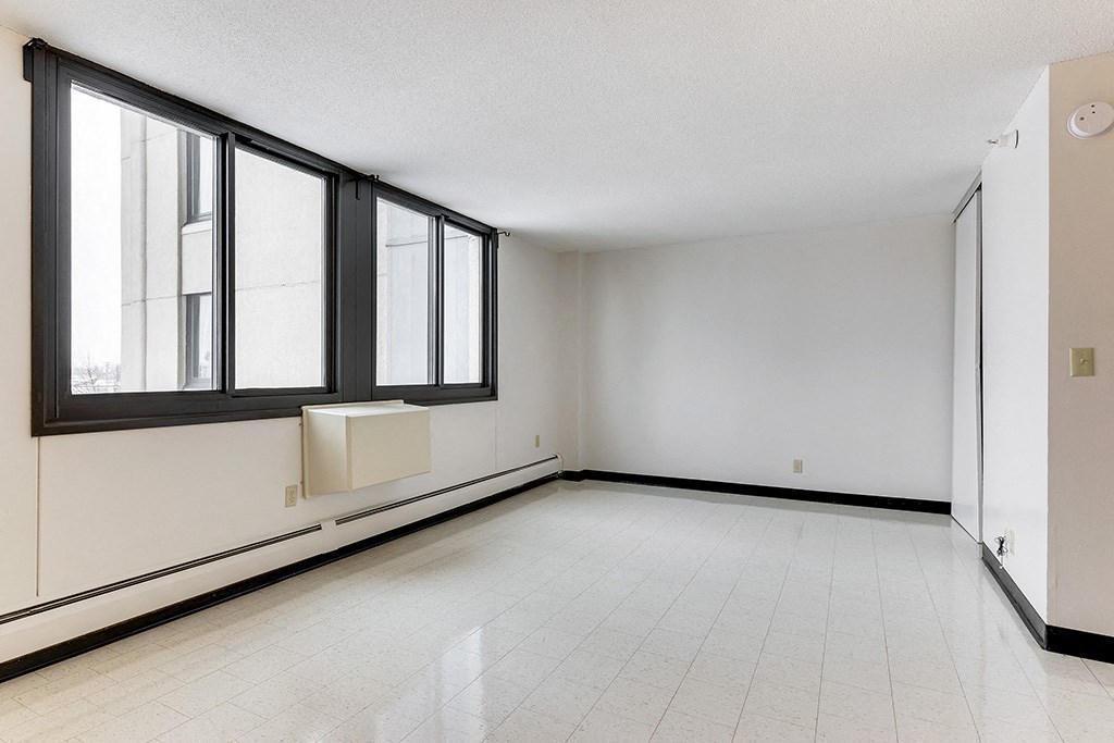 an empty living room with large windows and a white tiled floor