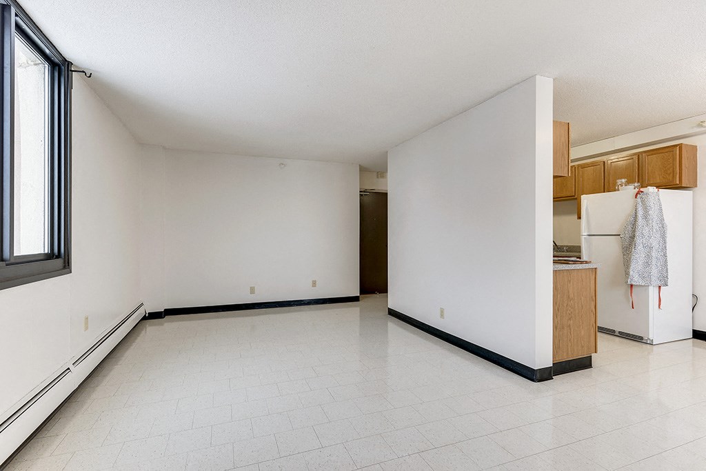 an empty room with a kitchen and a refrigerator
