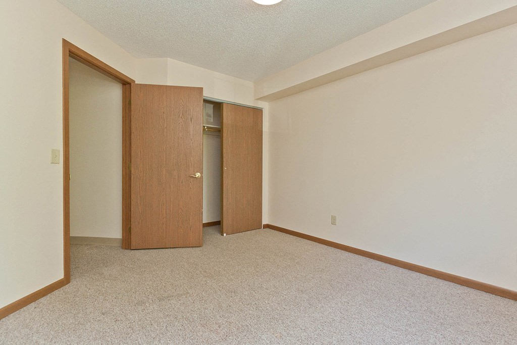 an empty living room with two doors to a closet