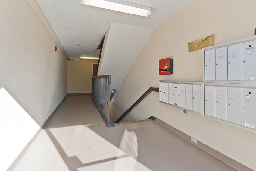 a long hallway with lockers and a staircase in a building