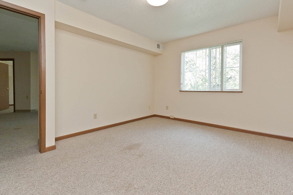 an empty living room with a window and carpet