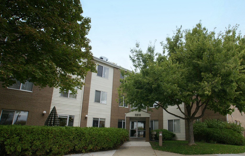 an apartment building with a sidewalk and trees