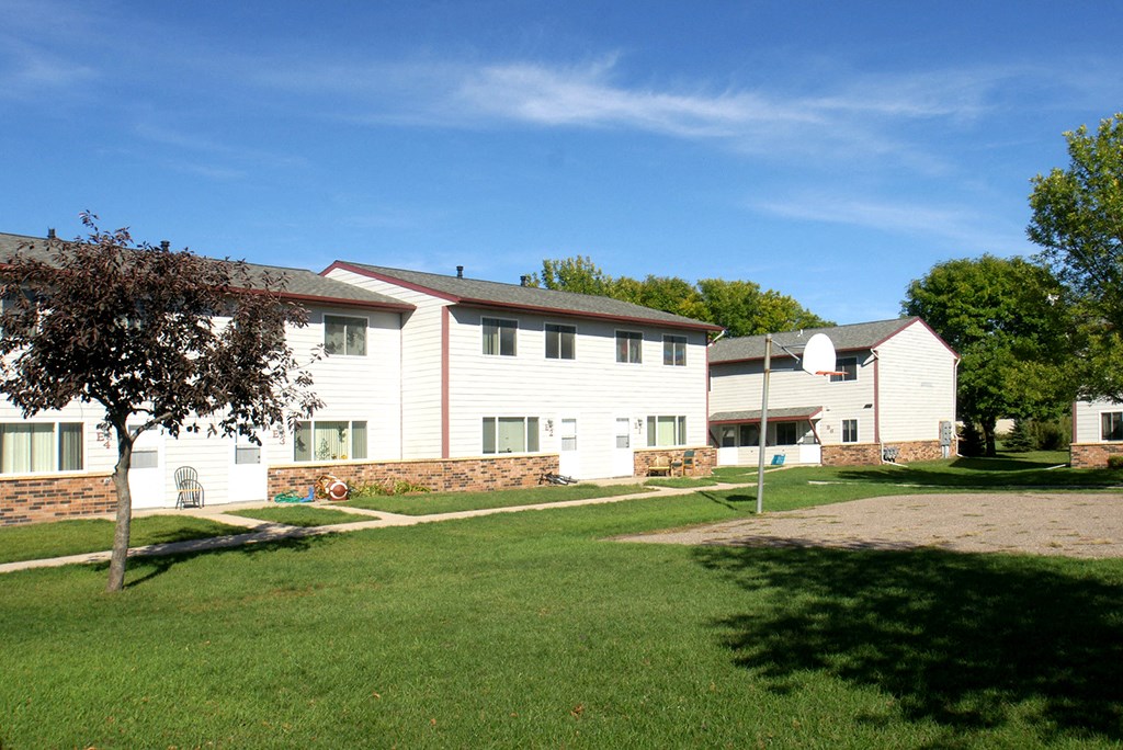 a group of white houses with a grass yard and a tree