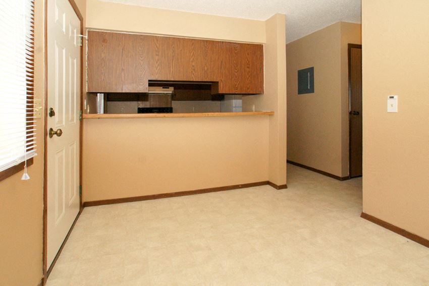 an empty room with a kitchen and a door to a hallway
