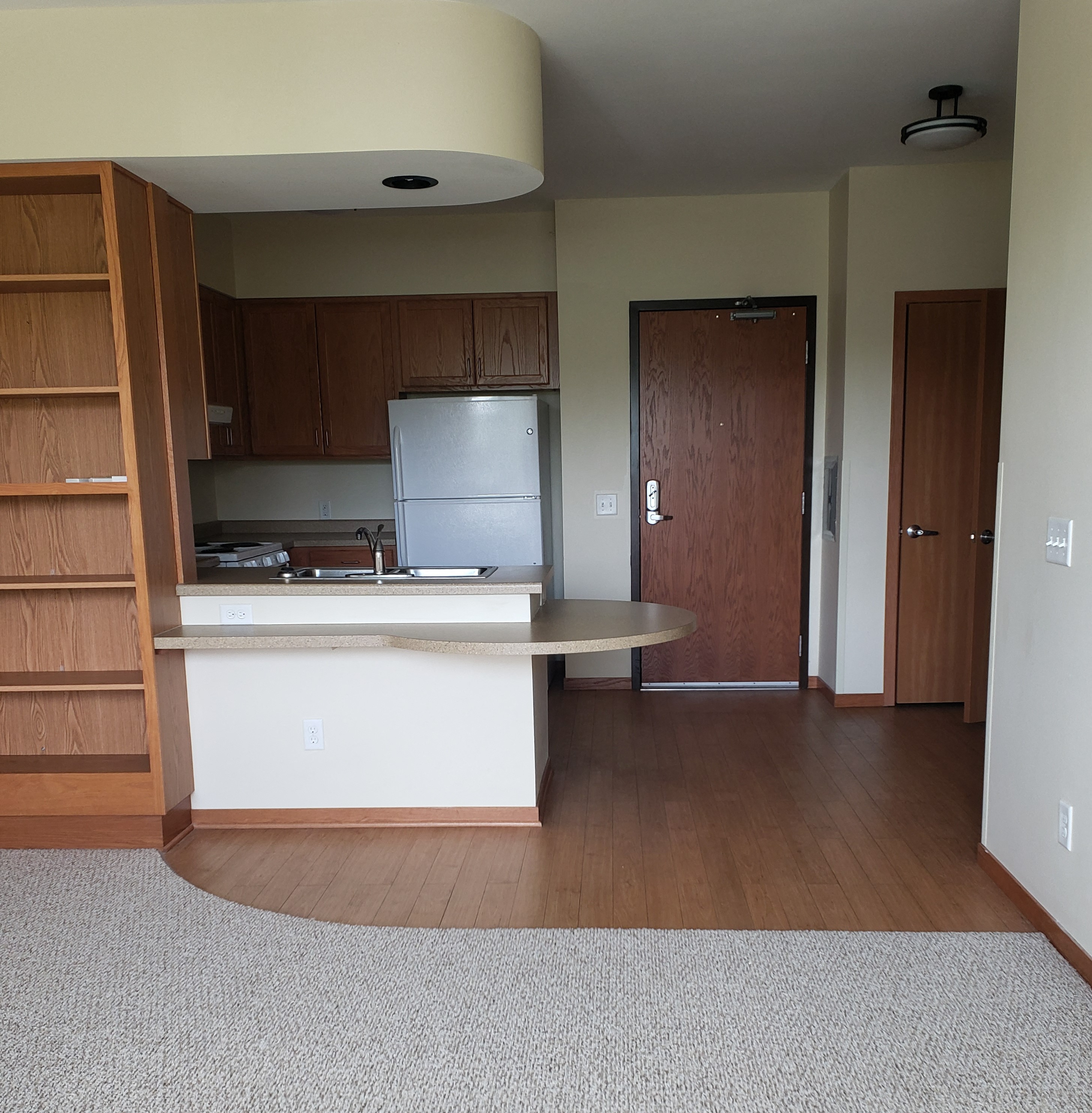 an empty kitchen with a table and a refrigerator in it
