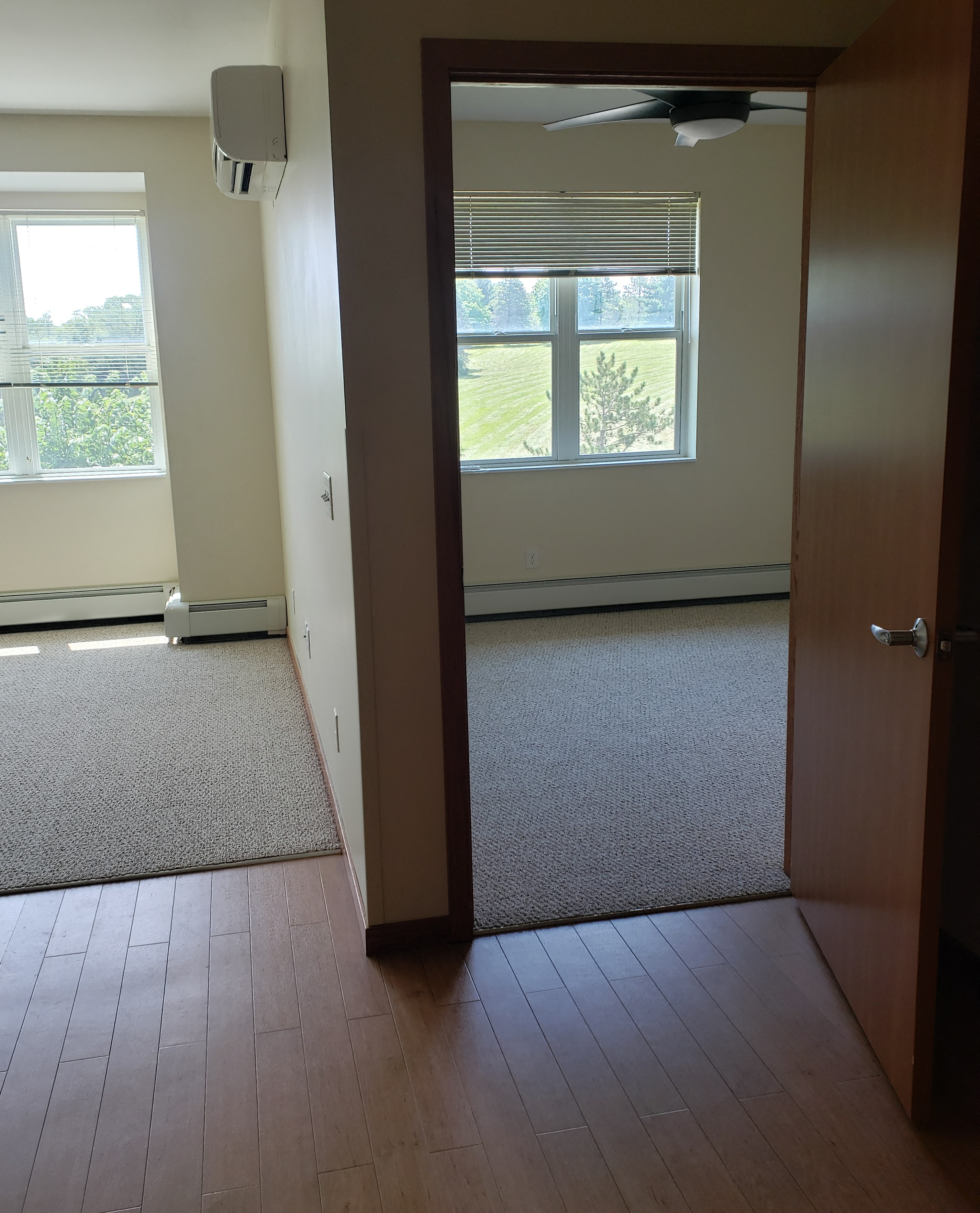 an open door looking into a living room with carpet and a window