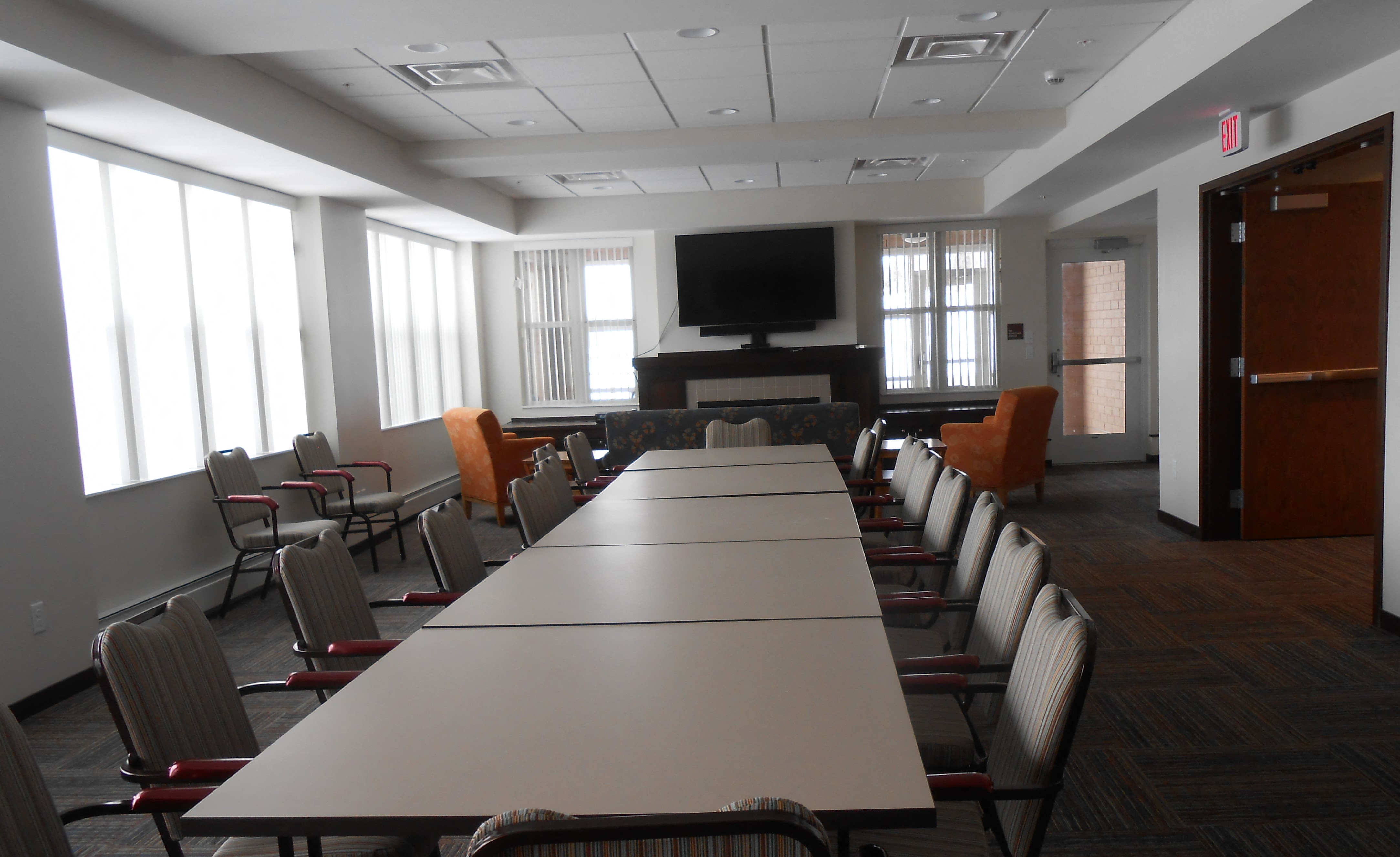 a conference room with a long table and chairs and a television in the corner
