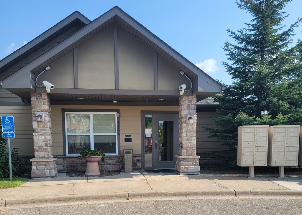 the front of a brown building with stone pillars and a blue sign