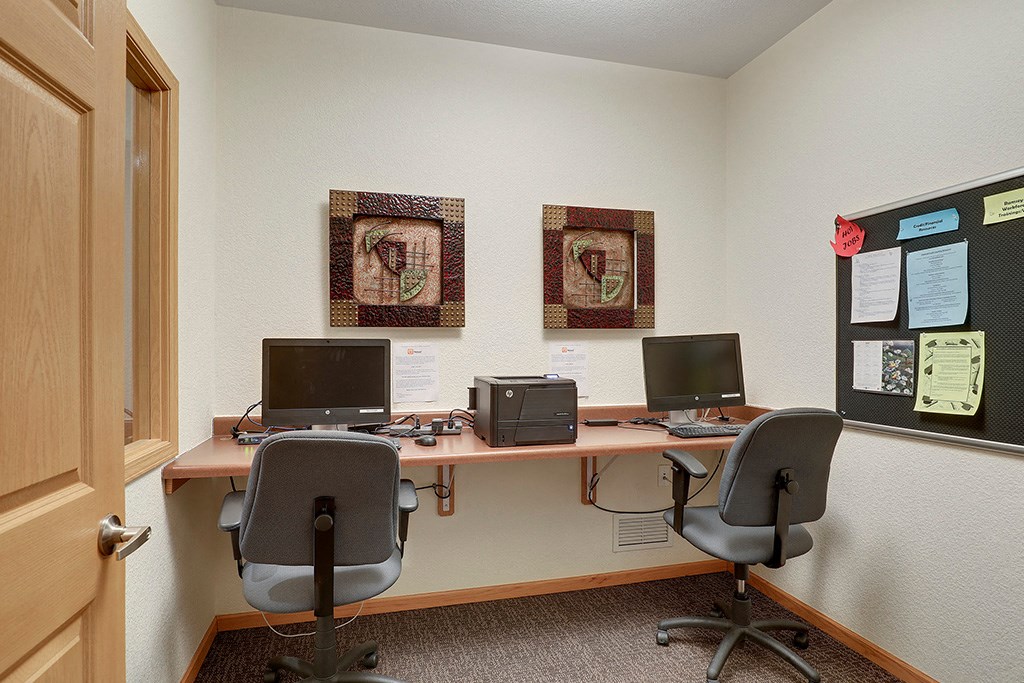 a desk with two computers and two chairs in a room