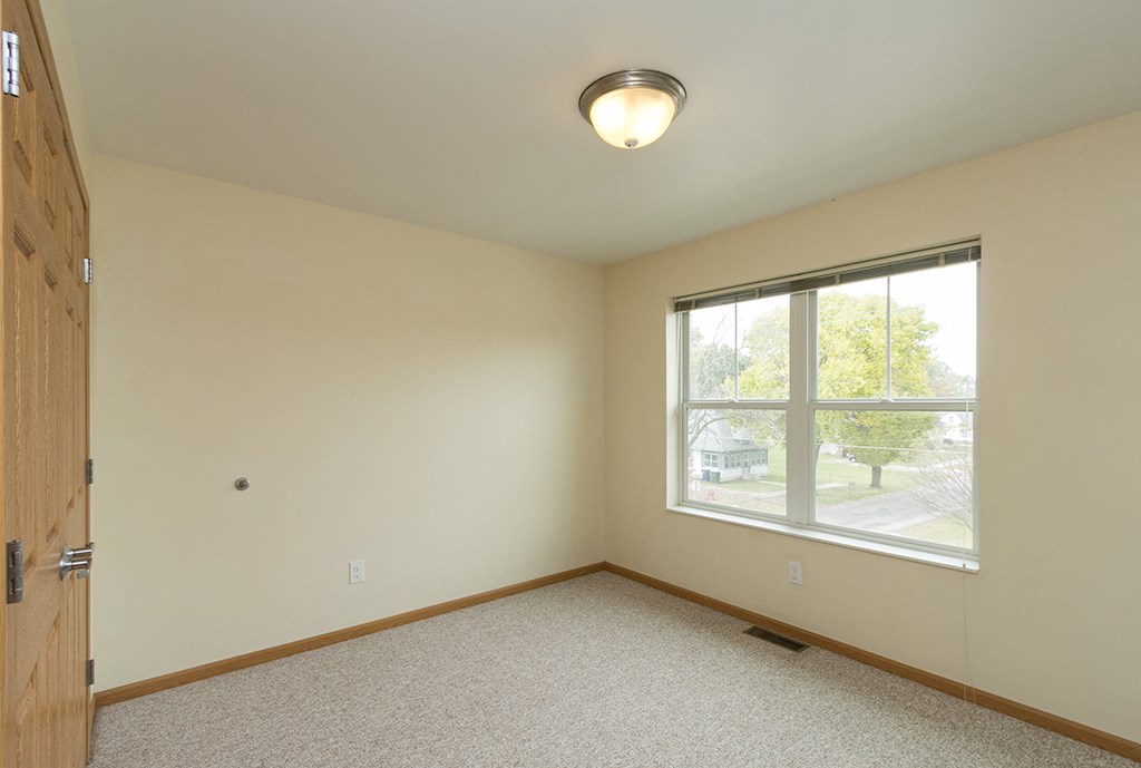 an empty bedroom with a large window and a door