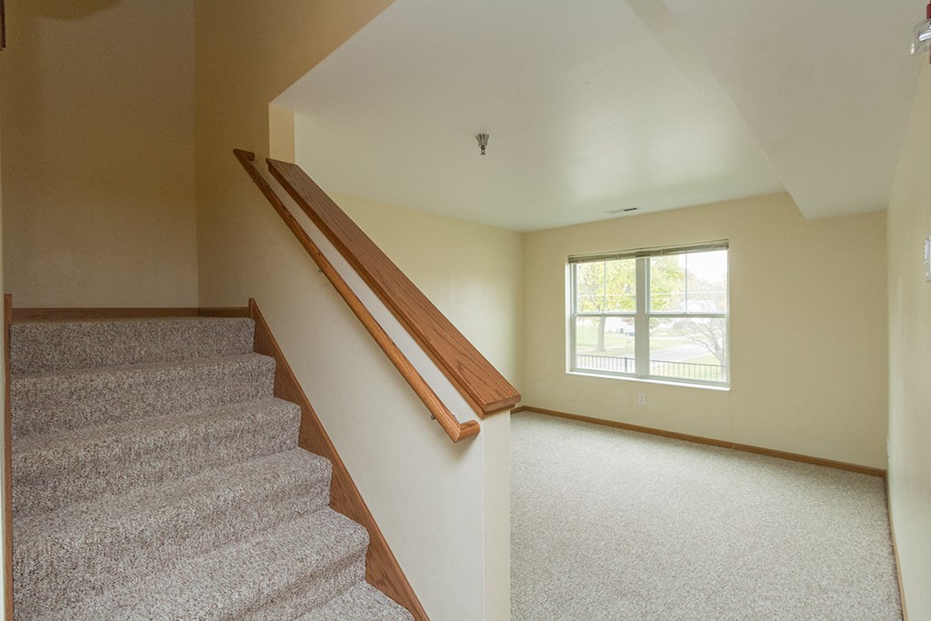 the landing of a staircase in a home with carpet and a window