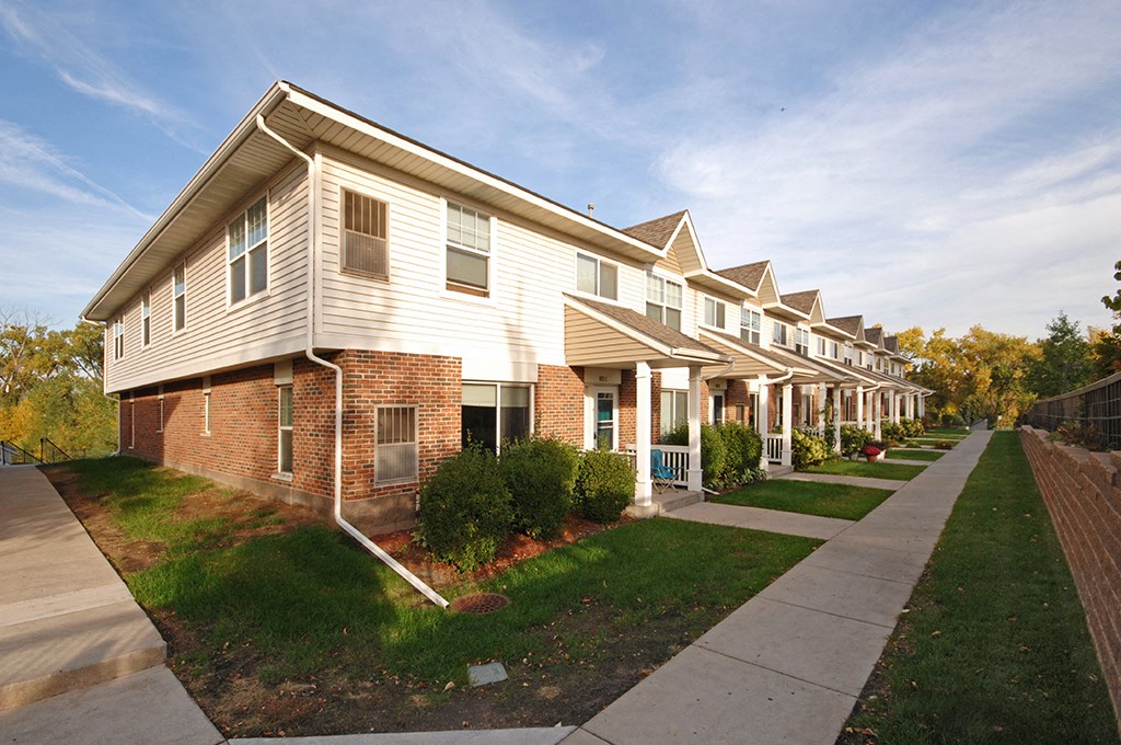 a row of town homes with white siding and a sidewalk