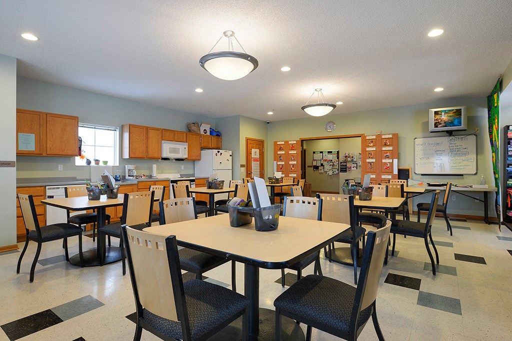 a dining room with tables and chairs and a kitchen