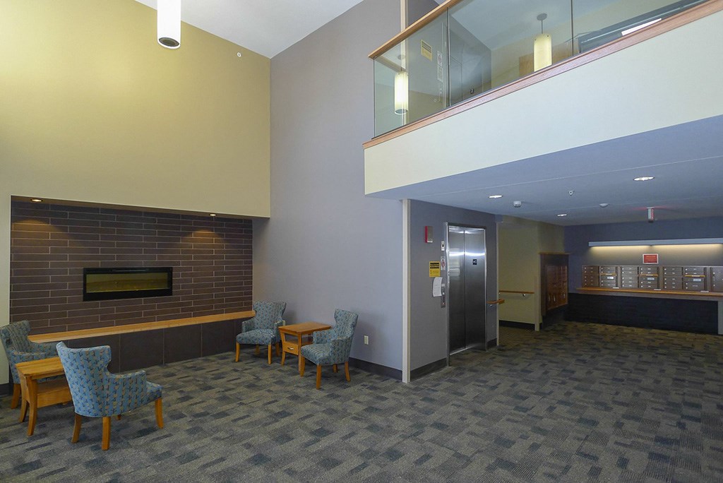 a lobby with chairs and a fireplace and an elevator