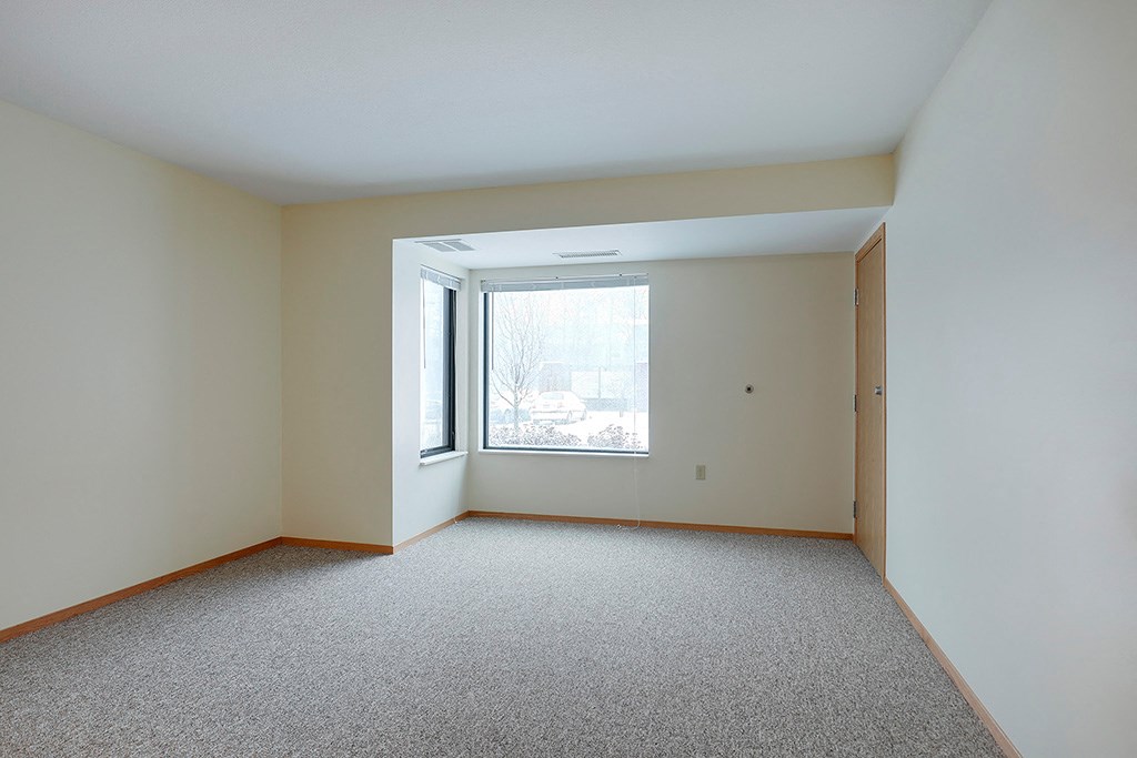 an empty room with a large window and carpet