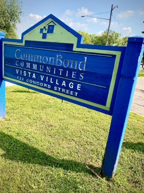a blue sign in the grass next to a street
