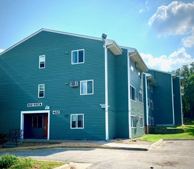 the front of a blue building with a parking lot