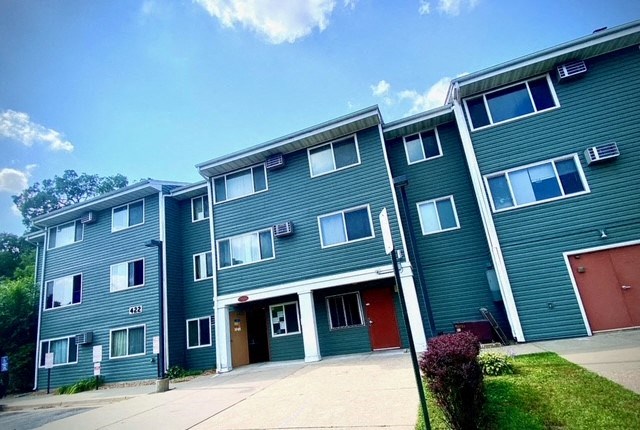 a row of green apartment buildings with a driveway