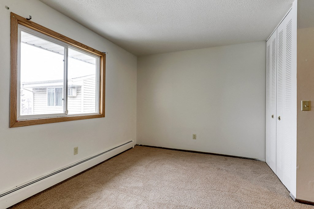 an empty living room with a large window and carpet