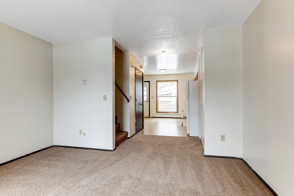 a living room with a carpeted floor and a hallway with a door to a
