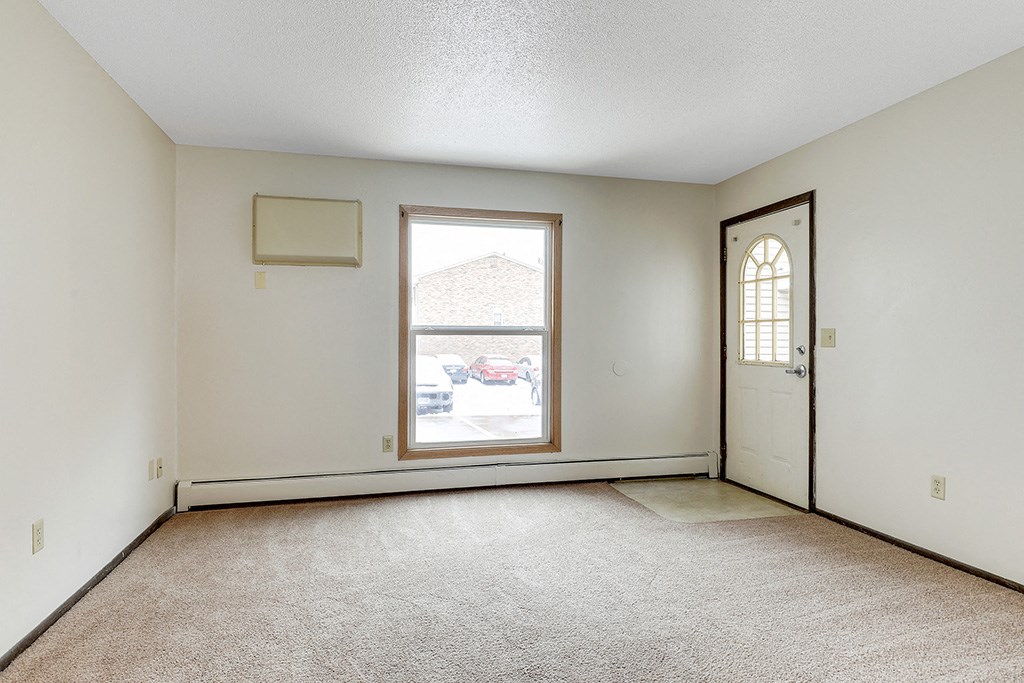 the living room of an empty house with a door and a window
