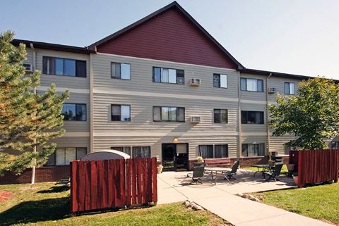 the exterior of an apartment building with a patio and patio furniture