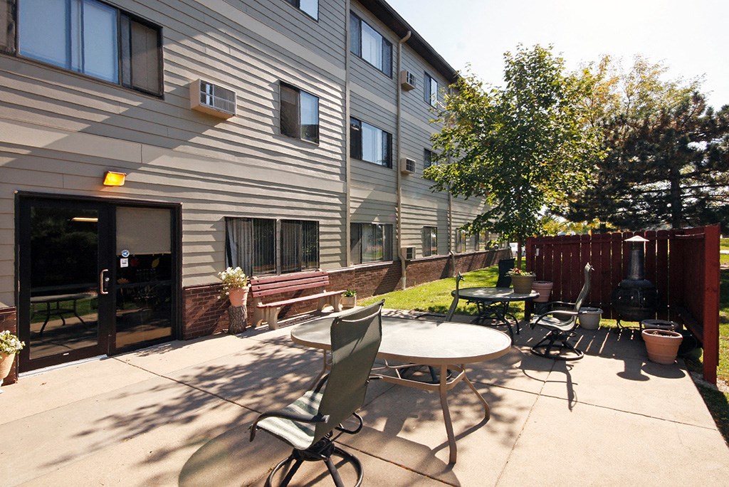 a patio with a table and chairs in front of a building