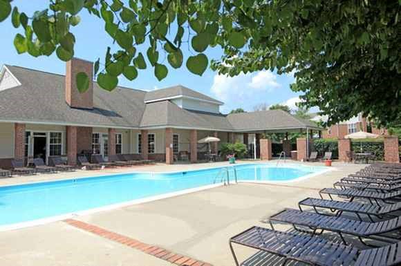 a swimming pool with chairs around it in front of a building