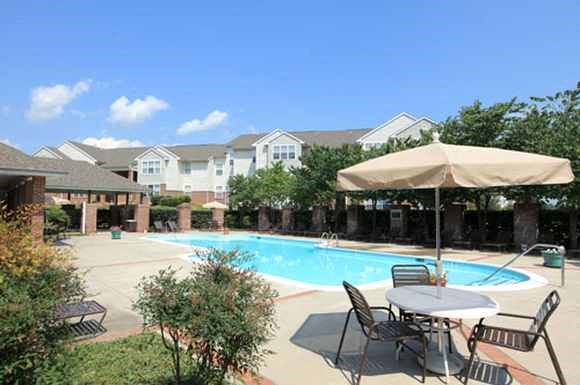 a swimming pool with a patio with chairs and an umbrella