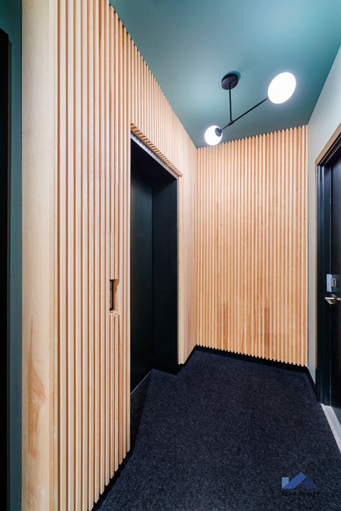 A hallway with a black carpet and wooden walls.